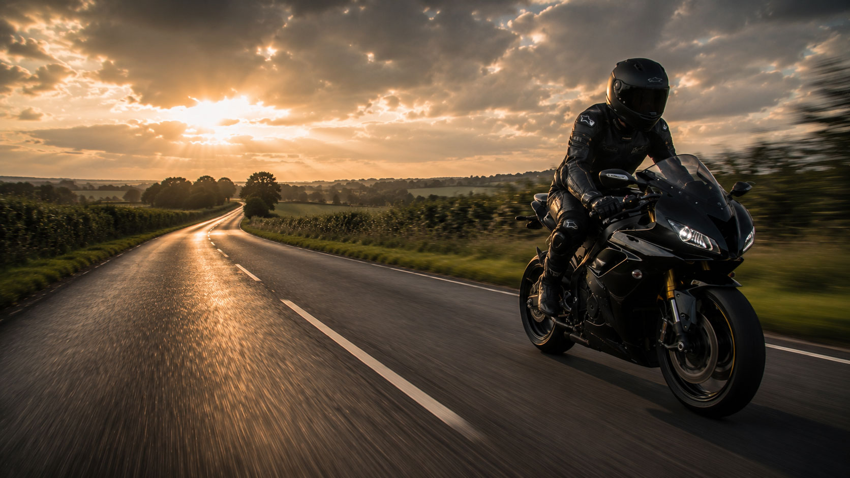New Motorcyclist riding down a road with the sunset in the background